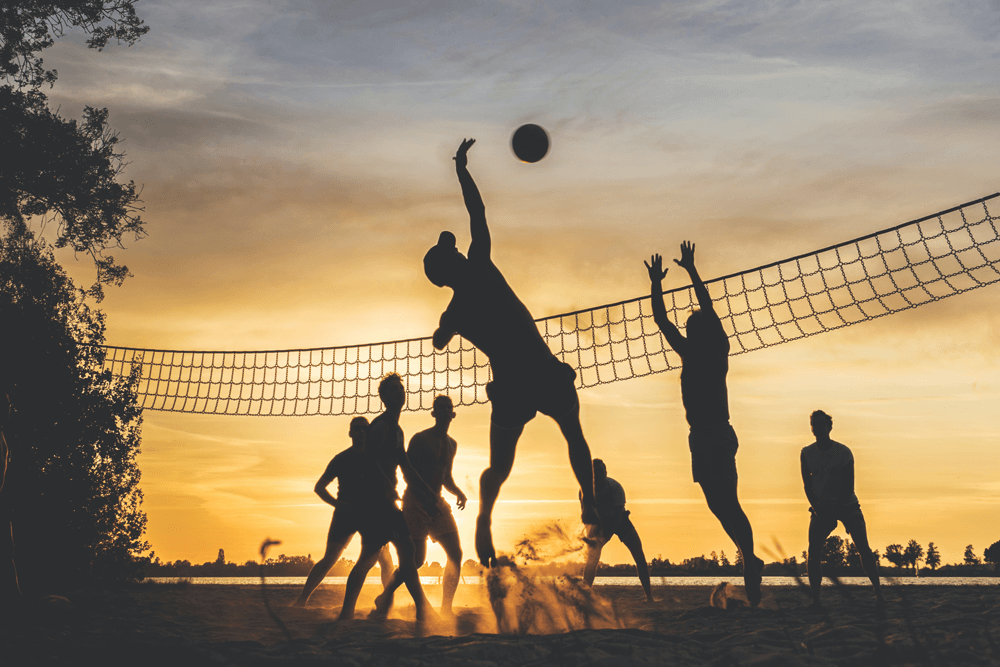 co-workers playing volleyball at beach